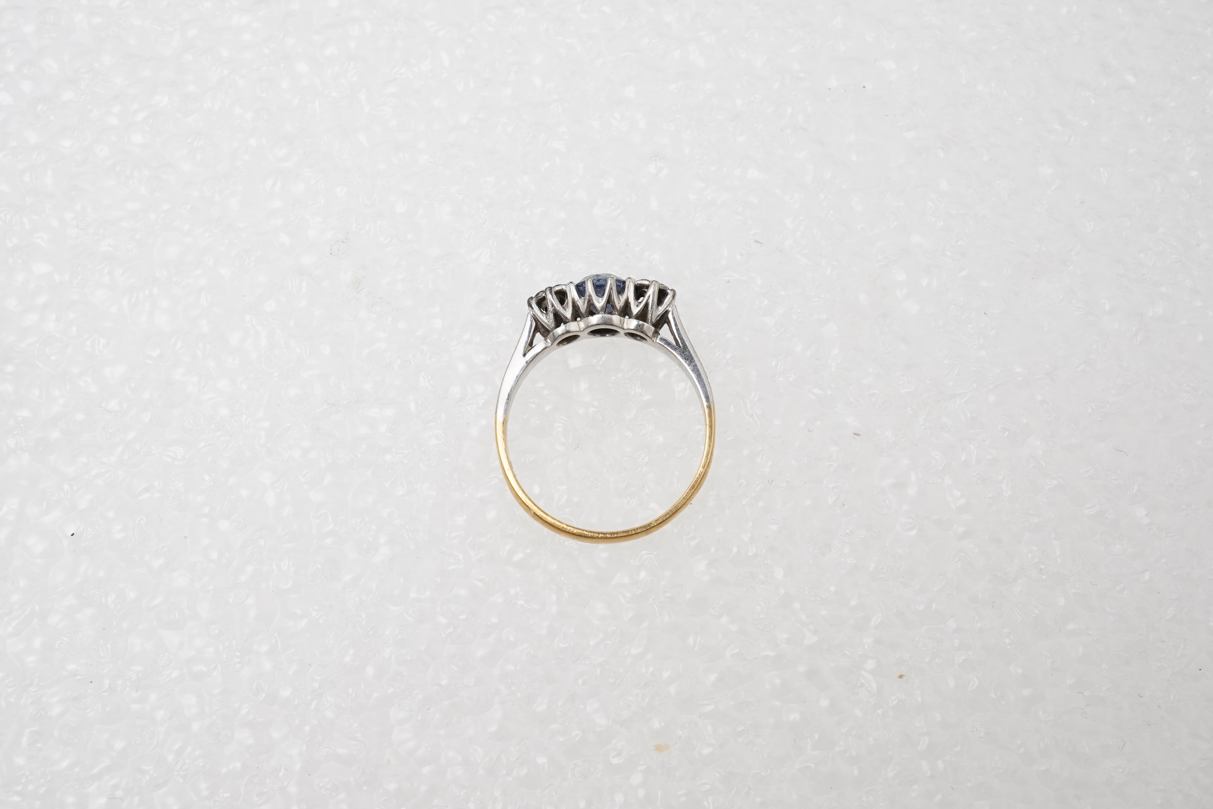 A sapphire and diamond three-stone ring, claw-set with a circular-cut sapphire measuring approximately 4.9 x 4.9 x 3.1mm, between single-cut diamonds totalling approximately 0.15 carats, mounted in gold and platinum, siz